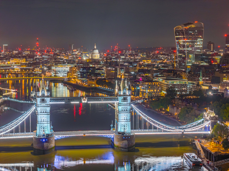 Aerial view of Tower Bridge illuminated at night over the River Thames with the City of London skyline in the background London England United Kingdom.