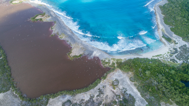 Aerial view of Los Roques archipelago featuring a turquoise Caribbean sea a dark lagoon white sand beaches and lush green vegetation in Los Roques Dependencias Federales Venezuela. Aerial view of Los Roques archipelago featuring a turquoise Caribbean sea a dark lagoon white sand beaches and lush green vegetation in Los Roques Dependencias Federales Venezuela.