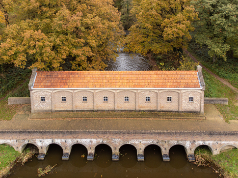 Aerial view of a quaint building with an orange roof and arched bridge nestled between golden autumn trees and a calm canal Tilligte Overijssel Netherlands. Aerial view of a quaint building with an orange roof and arched bridge nestled between golden autumn trees and a calm canal Tilligte Overijssel Netherlands.