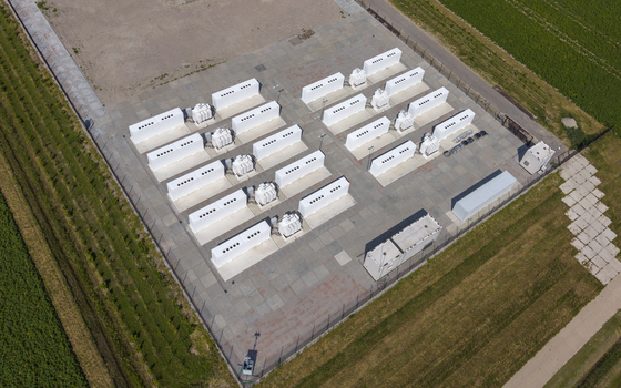 Aerial view of the Battery Energy Storage System at Wind Park featuring rows of white storage containers and transformers on a concrete pad in Dronten Flevoland Netherlands. Aerial view of the Battery Energy Storage System at Wind Park featuring rows of white storage containers and transformers on a concrete pad in Dronten Flevoland Netherlands.
