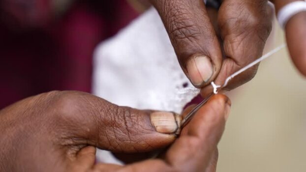 View of hands tying a white knot with thread Bangladesh. View of hands tying a white knot with thread Bangladesh.