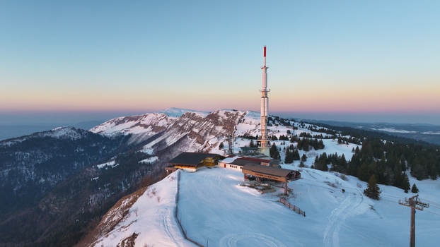 Aerial view of Mont Rond peak kissed by the soft glow of dawn with the Gex communication tower standing tall amidst the snowy landscape Gex Auvergne Rh&ocirc;ne Alpes France.