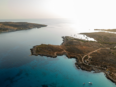 Aerial view of turquoise waters meeting rugged coastline boats dotting the horizon under a hazy sky Blue lagoon Comino Malta. Aerial view of turquoise waters meeting rugged coastline boats dotting the horizon under a hazy sky Blue lagoon Comino Malta.