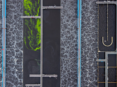 Aerial view of the Klarwerk Ruhleben sewage treatment plant featuring aeration tanks with bubbling water and green algae patterns alongside industrial walkways in Berlin Berlin Germany.