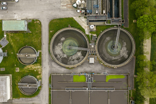 Aerial view of a wastewater treatment plant with circular sedimentation tanks and rectangular basins surrounded by green vegetation in San Giovanni Valdarno Tuscany Italy.