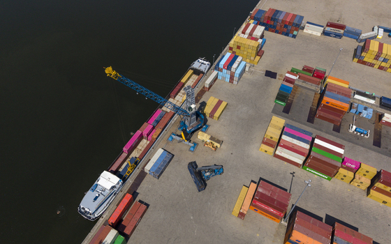 Aerial view of TMA Terminals Lelystad featuring a cargo ship docked at the quay surrounded by stacks of colorful shipping containers and industrial equipment in Lelystad Flevoland Netherlands. Aerial view of TMA Terminals Lelystad featuring a cargo ship docked at the quay surrounded by stacks of colorful shipping containers and industrial equipment in Lelystad Flevoland Netherlands.