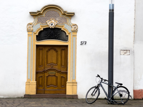 View of the ornate wooden entrance of the Karl Marx House with a bicycle parked against a lamp post on a cobblestone street in Trier Rheinland Pfalz Germany.