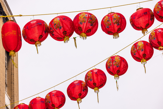 London United Kingdom 12 May 2025 View of red Chinese lanterns with golden dragon patterns hanging on strings against a pale sky in Chinatown.