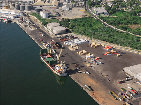 Aerial view of the industrial port of Haina with a cargo ship docked at the pier storage silos and trucks in Bajos de Haina San Cristobal Provinc Dominican Republic.