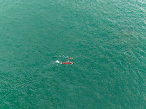 Aerial view of a small traditional fishing boat with fishermen moving across the turquoise sea in Galle Southern Province Sri Lanka.