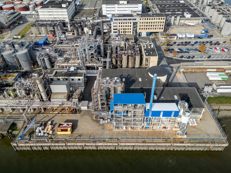 Aerial view of the industrial refinery complex featuring storage tanks pipelines and processing units located along the waterfront in Hamburg Germany.