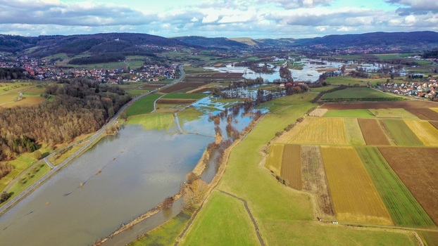 Aerial view of flooded fields and an overflowing river surrounded by rolling hills rural landscapes and small villages under a cloudy sky Forchheim Bavaria Germany. Aerial view of flooded fields and an overflowing river surrounded by rolling hills rural landscapes and small villages under a cloudy sky Forchheim Bavaria Germany.