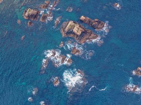 Aerial view of the jagged rocky formations and turquoise sea water at Silence Beach Viewpoint with white foam from waves crashing against the stones in Cudillero Asturias Spain.