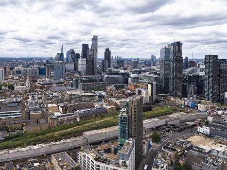 Aerial view of the Shoreditch district and the modern London skyline featuring glass skyscrapers dense urban architecture and railway tracks under a cloudy sky in London England United Kingdom. Aerial view of the Shoreditch district and the modern London skyline featuring glass skyscrapers dense urban architecture and railway tracks under a cloudy sky in London England United Kingdom.