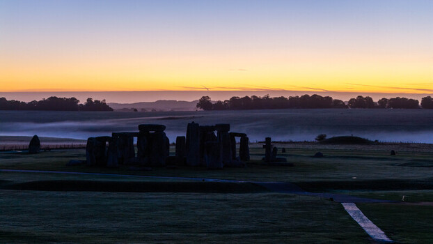 Aerial view of Stonehenge standing in the misty landscape during sunrise with golden light illuminating the horizon Salisbury England United Kingdom. Aerial view of Stonehenge standing in the misty landscape during sunrise with golden light illuminating the horizon Salisbury England United Kingdom.