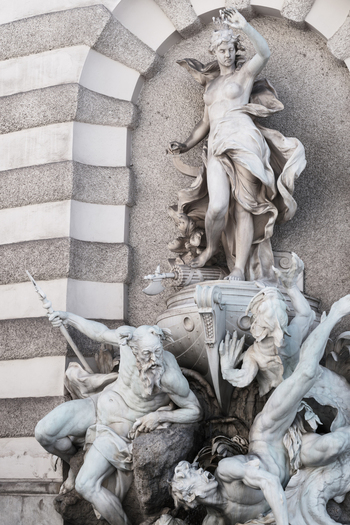 View of the Power at Sea fountain featuring dramatic marble statues and intricate architectural details at the Hofburg Palace in Vienna Austria. View of the Power at Sea fountain featuring dramatic marble statues and intricate architectural details at the Hofburg Palace in Vienna Austria.