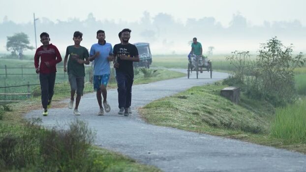 View of young men jogging on a misty rural road Bangladesh.