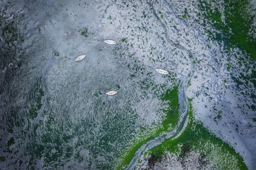 Aerial view of small white boats moored on the textured tidal flats of Bull Island with vibrant green algae and grey sand patterns in County Dublin Ireland. Aerial view of small white boats moored on the textured tidal flats of Bull Island with vibrant green algae and grey sand patterns in County Dublin Ireland.