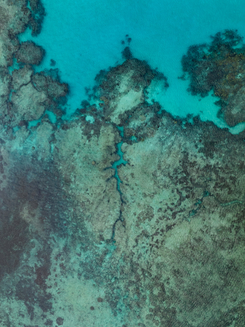 Aerial view of turquoise waters meet the rugged coral reefs below creating a mesmerizing dance of light and shadow Hunete Loyalty Islands Province New Caledonia. Aerial view of turquoise waters meet the rugged coral reefs below creating a mesmerizing dance of light and shadow Hunete Loyalty Islands Province New Caledonia.