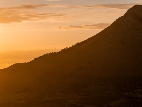 Aerial view of Riserva Naturale Orientata dello Zingaro at sunset with golden light illuminating the mountain slopes and sparse vegetation in San Vito Lo Capo Sicilia Italy. Aerial view of Riserva Naturale Orientata dello Zingaro at sunset with golden light illuminating the mountain slopes and sparse vegetation in San Vito Lo Capo Sicilia Italy.