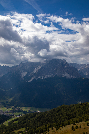 View of the majestic Dolomites mountain range with jagged peaks partially shrouded in dramatic clouds above forested slopes and a valley in Rocca Pietore Veneto Italy. View of the majestic Dolomites mountain range with jagged peaks partially shrouded in dramatic clouds above forested slopes and a valley in Rocca Pietore Veneto Italy.