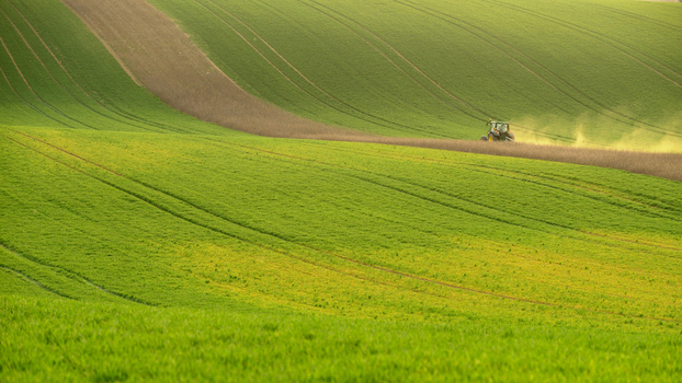 View of a tractor cultivating a rolling green field in the Moravia region Brno City District South Moravian Region Czechia.
