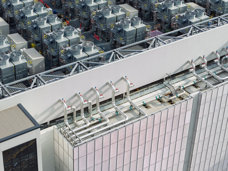 Aerial view of a data center rooftop featuring numerous industrial cooling fans and complex metal piping systems United Kingdom. Aerial view of a data center rooftop featuring numerous industrial cooling fans and complex metal piping systems United Kingdom.