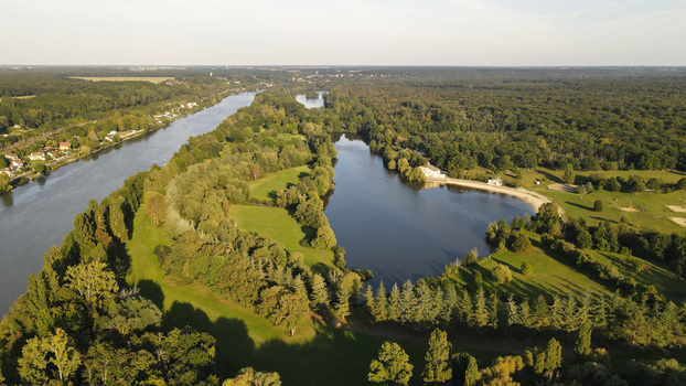 Aerial view of the Seine river flowing past a lush forested island and green parklands in Chartrettes Ile de France France. Aerial view of the Seine river flowing past a lush forested island and green parklands in Chartrettes Ile de France France.
