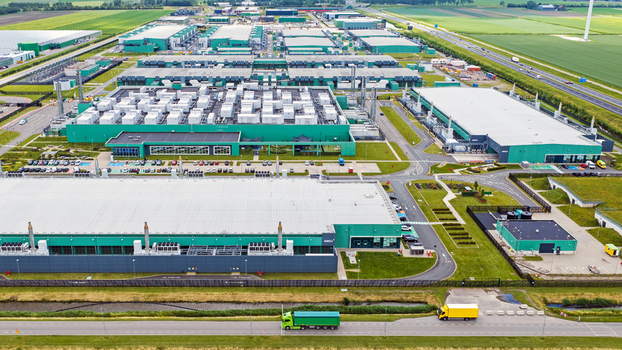 Aerial view of a large data center complex with industrial buildings cooling units and parking areas surrounded by green fields in Middenmeer North Holland Netherlands.