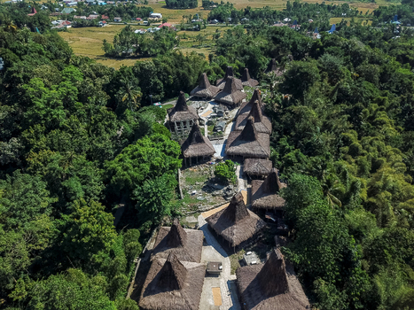 Aerial view of Praijing Village with its traditional houses featuring high thatched roofs nestled within lush green forest in Kota Walkabubak East Nusa Tenggara Indonesia. Aerial view of Praijing Village with its traditional houses featuring high thatched roofs nestled within lush green forest in Kota Walkabubak East Nusa Tenggara Indonesia.