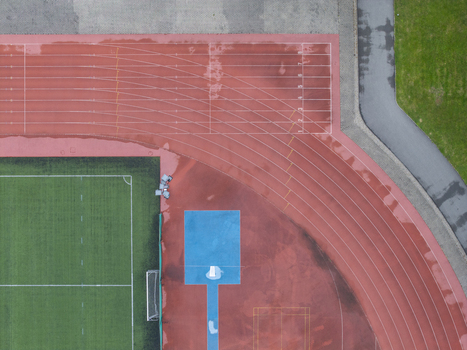 Aerial view of a wet running track and sports center with artificial turf and a blue long jump pit after rain in Wieliczka Lesser Poland Voivodeship Poland. Aerial view of a wet running track and sports center with artificial turf and a blue long jump pit after rain in Wieliczka Lesser Poland Voivodeship Poland.