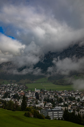 Aerial view of the town of Airolo nestled in the Swiss Alps with lush green meadows dense forests and dramatic clouds clinging to the mountain slopes in Airolo Ticino Switzerland. Aerial view of the town of Airolo nestled in the Swiss Alps with lush green meadows dense forests and dramatic clouds clinging to the mountain slopes in Airolo Ticino Switzerland.