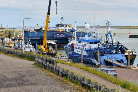 Den Oever Netherlands 18 May 2026 View of British fleet vessels being renovated at the Machinefabriek Luyt fishing repair wharf with a large yellow crane in the harbor.