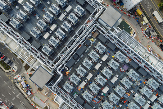 Aerial view of a data center roof featuring numerous industrial HVAC cooling units and complex piping systems in the United Kingdom. Aerial view of a data center roof featuring numerous industrial HVAC cooling units and complex piping systems in the United Kingdom.