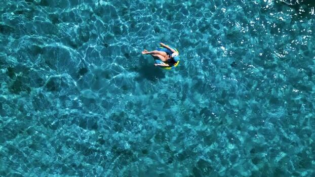 Aerial view of a person floating in turquoise water Honduras.