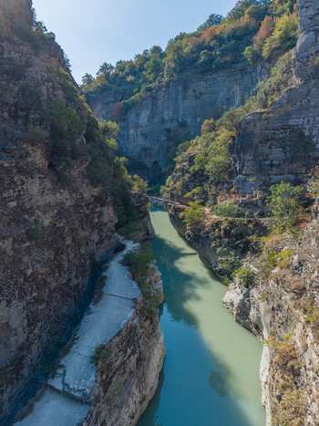 Aerial view of Osumi Canyon with its steep limestone cliffs lush green vegetation and the river flowing through the narrow gorge in Dhores Berat County Albania.