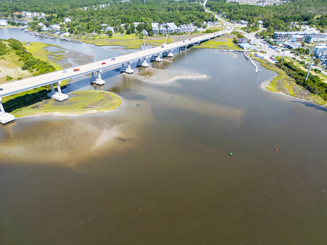 Aerial view of North Topsail Bridge spanning the waterway with surrounding marshlands coastal vegetation and nearby residential buildings in North Topsail Beach North Carolina United States.