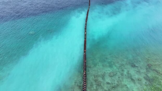 Aerial view of a pipeline in turquoise ocean water Maldives.