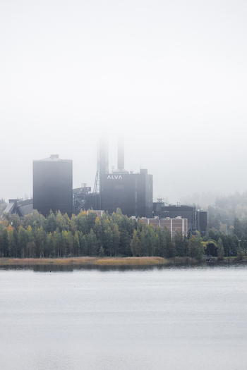 View of the Alva power plant facility partially obscured by thick morning fog surrounded by autumn trees along the lake shore in Jyvaskyla Central Finland Finland.