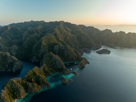 Aerial view of the Twin Lagoon surrounded by dramatic limestone cliffs and turquoise waters at sunset in Coron Mimaropa Philippines. Aerial view of the Twin Lagoon surrounded by dramatic limestone cliffs and turquoise waters at sunset in Coron Mimaropa Philippines.