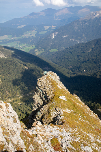 View of a sharp rocky ridge overlooking a deep forested valley and distant mountain peaks in the Dolomites Rocca Pietore Veneto Italy. View of a sharp rocky ridge overlooking a deep forested valley and distant mountain peaks in the Dolomites Rocca Pietore Veneto Italy.