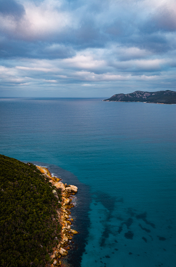 Aerial view of Bettys Beach featuring turquoise waters rocky coastline and lush vegetation under a cloudy sky in Albany WA Australia. Aerial view of Bettys Beach featuring turquoise waters rocky coastline and lush vegetation under a cloudy sky in Albany WA Australia.