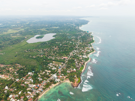 Aerial view of the tropical coastline featuring turquoise ocean waves sandy beaches and lush palm trees surrounding the coastal town Mirissa Southern Province Sri Lanka. Aerial view of the tropical coastline featuring turquoise ocean waves sandy beaches and lush palm trees surrounding the coastal town Mirissa Southern Province Sri Lanka.