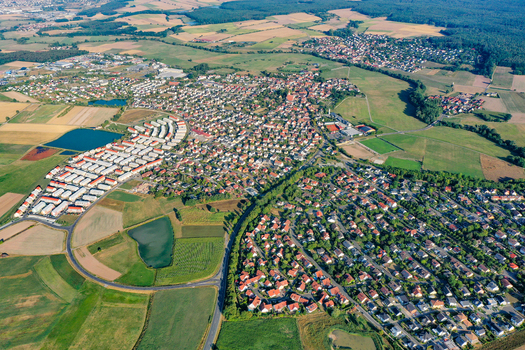 Aerial view of the town of Adelsdorf featuring residential neighborhoods with red roofed houses surrounded by lush green fields forests and small ponds in Adelsdorf Bavaria Germany. Aerial view of the town of Adelsdorf featuring residential neighborhoods with red roofed houses surrounded by lush green fields forests and small ponds in Adelsdorf Bavaria Germany.