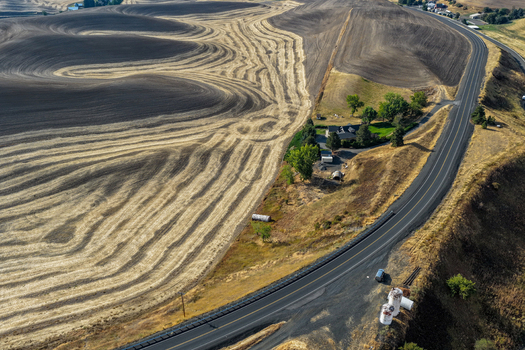 Aerial view of the rolling hills and harvested wheat fields of the Palouse region with a winding road a small farmhouse and storage tanks in Palouse Washington United States. Aerial view of the rolling hills and harvested wheat fields of the Palouse region with a winding road a small farmhouse and storage tanks in Palouse Washington United States.