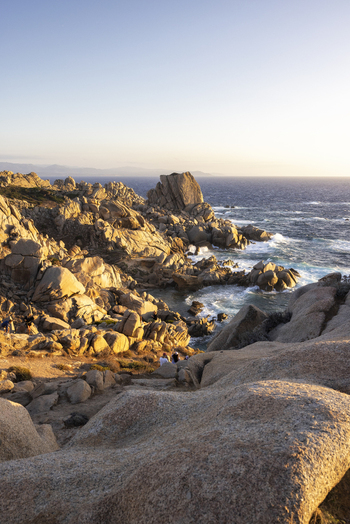 View of Capo Testa granite rock formations and the Mediterranean sea during sunset with people walking on the cliffs Capo Testa Sardegna Italy. View of Capo Testa granite rock formations and the Mediterranean sea during sunset with people walking on the cliffs Capo Testa Sardegna Italy.