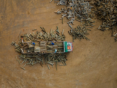 Aerial view of workers loading logs onto a truck in a large dirt yard in Boyolali Central Java Indonesia.