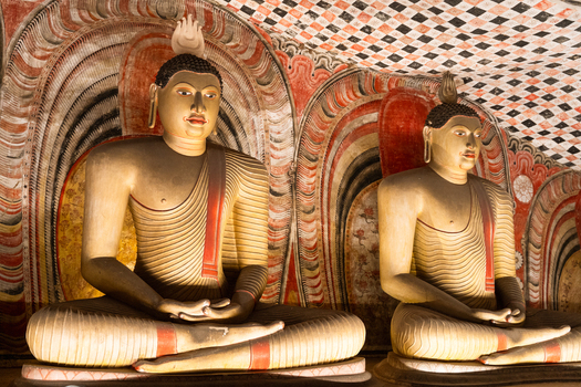 View of ancient seated Buddha statues with intricate murals in the Dambulla Cave Temple Dambulla Central Province Sri Lanka.