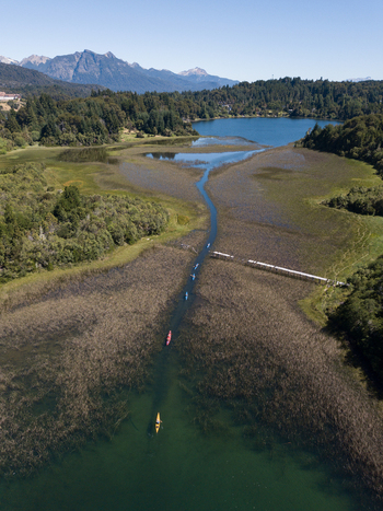 Aerial view of Nahuel Huapi Lake with kayakers paddling through a narrow channel surrounded by dense forest and mountains San Carlos de Bariloche Rio Negro Argentina. Aerial view of Nahuel Huapi Lake with kayakers paddling through a narrow channel surrounded by dense forest and mountains San Carlos de Bariloche Rio Negro Argentina.