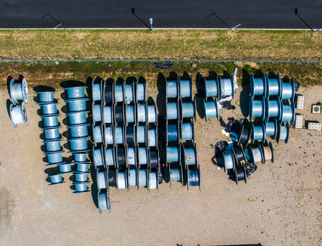Aerial view of numerous industrial cable reels arranged in rows at the Daniken storage area with gravel ground and a paved road nearby in Daniken Solothurn Switzerland.